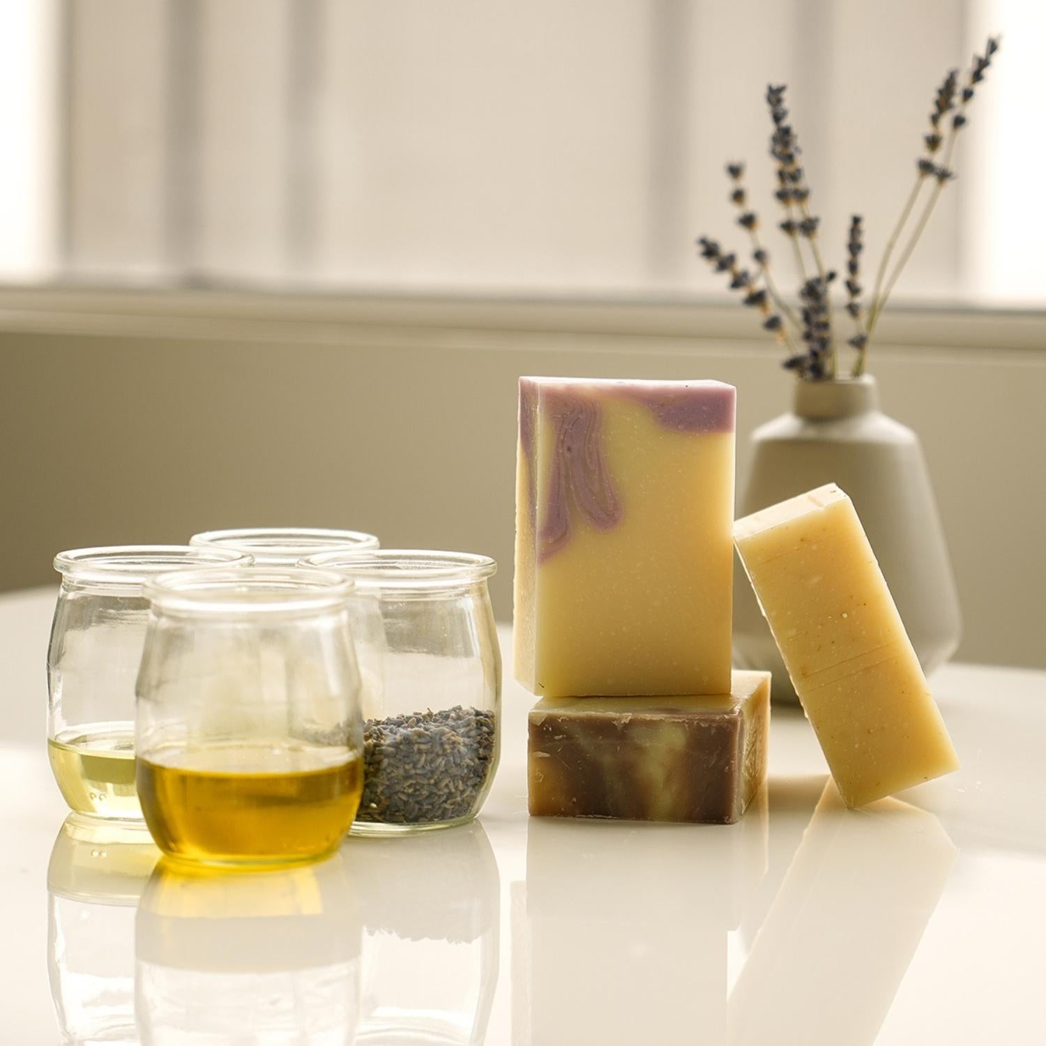 Trois savons artisanaux avec 4 pots qui contiennent des ingrédients naturels